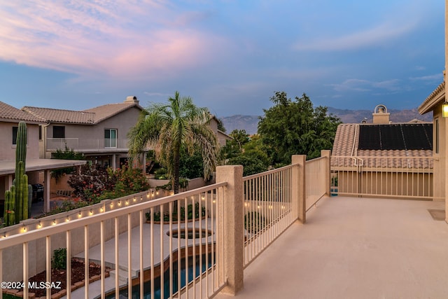 balcony at dusk featuring a mountain view and a fenced in pool