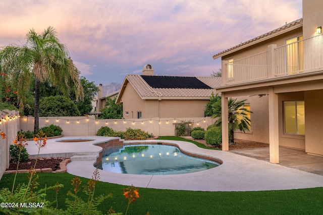 pool at dusk featuring a patio area and an in ground hot tub