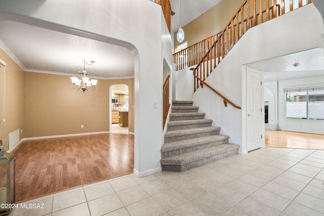 staircase with light hardwood / wood-style flooring, crown molding, and a chandelier