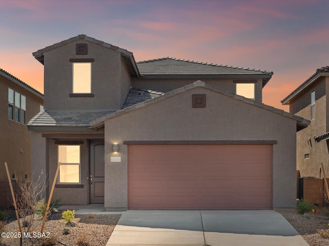 traditional home with driveway, an attached garage, a tile roof, and stucco siding