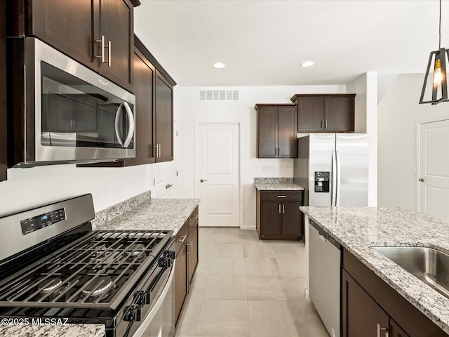 7005 W Jadewood Ln W, Tucson, AZ 85757 - kitchen with visible vents, light stone countertops, dark brown cabinetry, appliances with stainless steel finishes, and hanging light fixtures