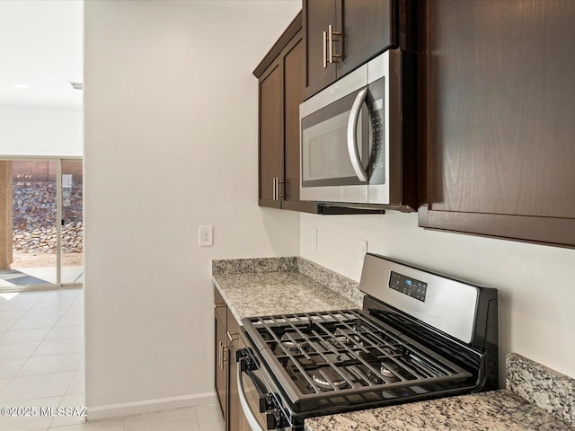 7005 W Jadewood Ln W, Tucson, AZ 85757 - kitchen featuring visible vents, stainless steel appliances, dark brown cabinetry, light tile patterned floors, and baseboards
