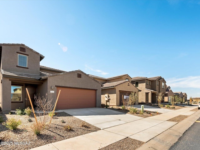 view of front of property featuring concrete driveway, a residential view, a tiled roof, an attached garage, and stucco siding