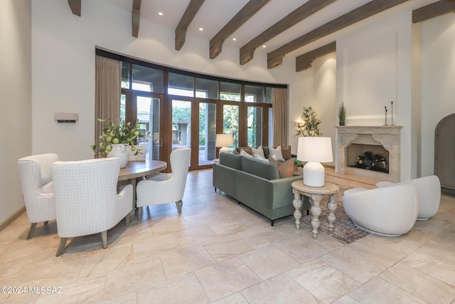 living room with french doors, a premium fireplace, and beamed ceiling