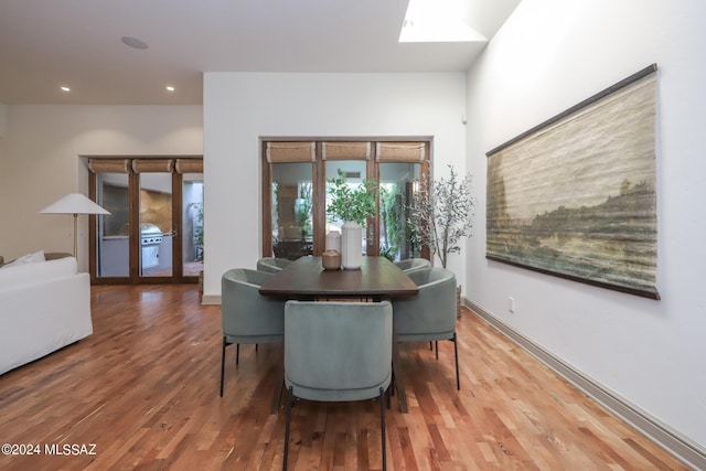 dining space with a skylight and hardwood / wood-style floors