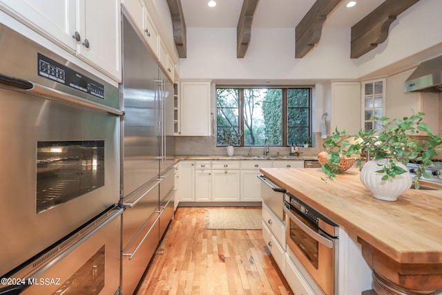 kitchen with white cabinets, wooden counters, beam ceiling, and appliances with stainless steel finishes