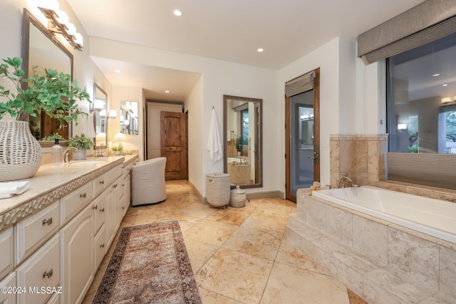 bathroom with a relaxing tiled tub and vanity