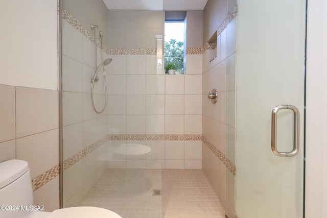 bathroom featuring a shower with door and toilet