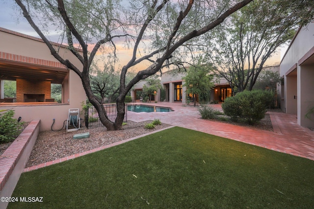 yard at dusk featuring an outdoor fireplace and a patio area