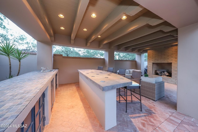 view of patio with a bar and an outdoor brick fireplace