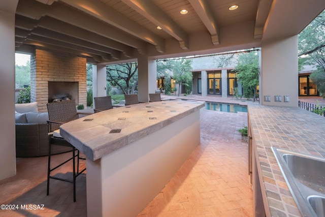 view of patio with an outdoor brick fireplace and a wet bar