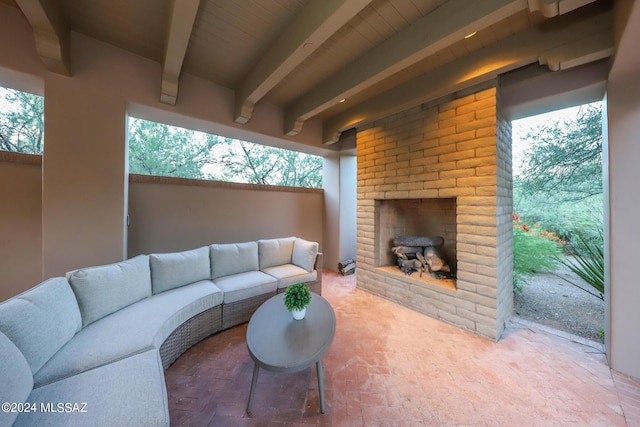 living room with an outdoor brick fireplace and beamed ceiling