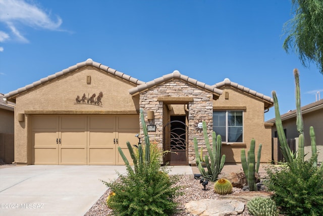 view of front of house with stucco siding, an attached garage, stone siding, driveway, and a tiled roof