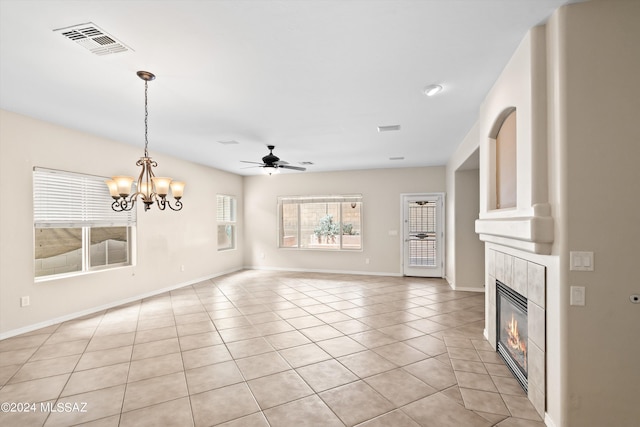 unfurnished living room with a tiled fireplace, ceiling fan with notable chandelier, and light tile patterned flooring