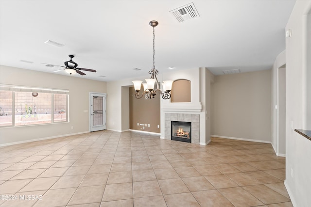 unfurnished living room with a fireplace, ceiling fan with notable chandelier, and light tile patterned flooring