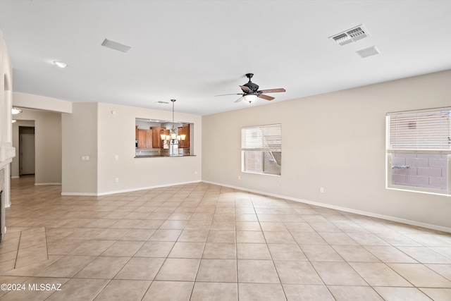 unfurnished room featuring ceiling fan with notable chandelier and light tile patterned flooring