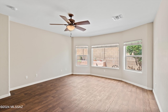 spare room with a healthy amount of sunlight, ceiling fan, and dark hardwood / wood-style flooring