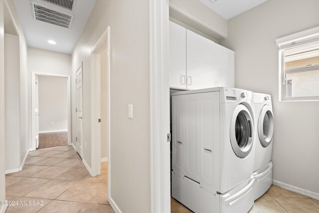 clothes washing area featuring light tile patterned floors, independent washer and dryer, and cabinets