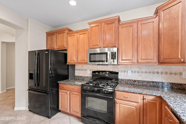 kitchen featuring black appliances, backsplash, light tile patterned floors, and dark stone countertops