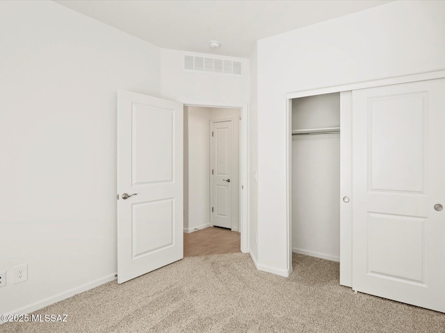 unfurnished bedroom featuring carpet, visible vents, a closet, and baseboards