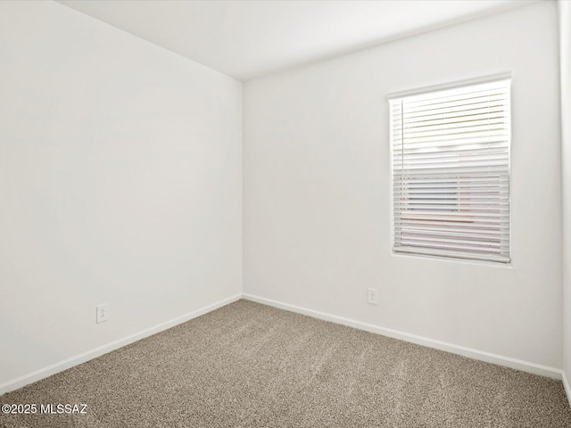 carpeted empty room featuring baseboards