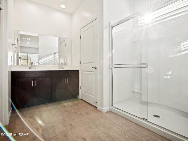 full bath with wood tiled floor, a sink, and a shower stall