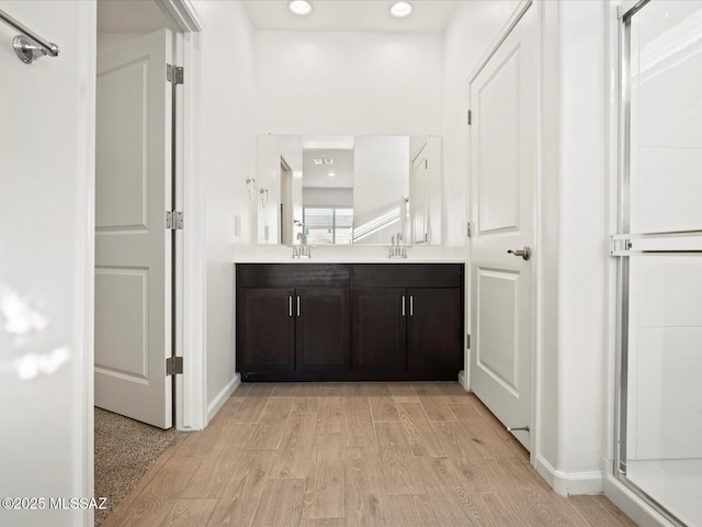 full bath with double vanity, recessed lighting, wood finished floors, and a sink