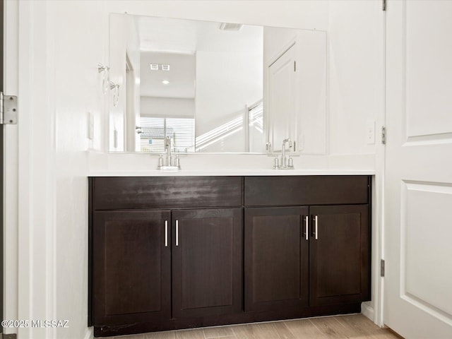 full bathroom featuring visible vents, a sink, wood finished floors, and double vanity