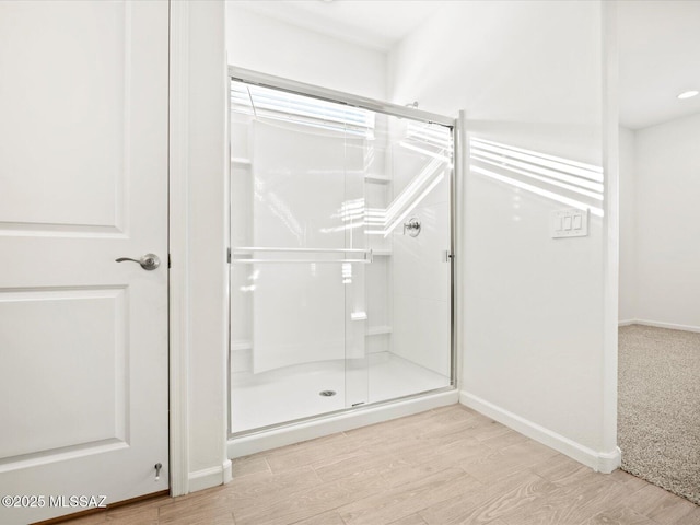 full bath featuring wood finished floors, a stall shower, and baseboards