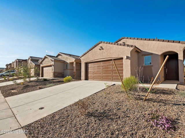 view of front of house with stucco siding, a garage, concrete driveway, and a tiled roof