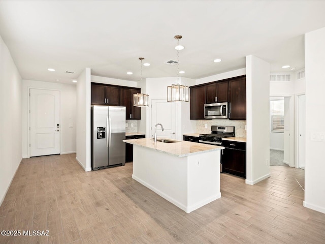 kitchen featuring an inviting chandelier, a sink, decorative backsplash, dark brown cabinetry, and stainless steel appliances