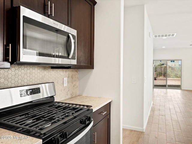 kitchen with visible vents, baseboards, dark brown cabinets, appliances with stainless steel finishes, and tasteful backsplash