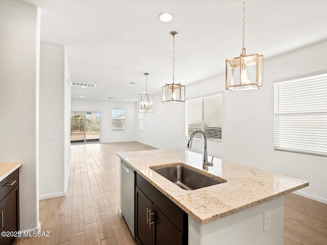 kitchen featuring visible vents, dishwasher, light wood-style floors, and a sink