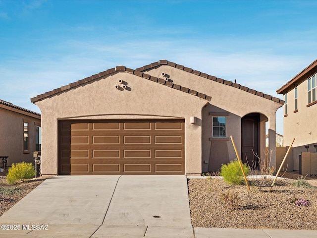 mediterranean / spanish-style house with an attached garage, driveway, and stucco siding