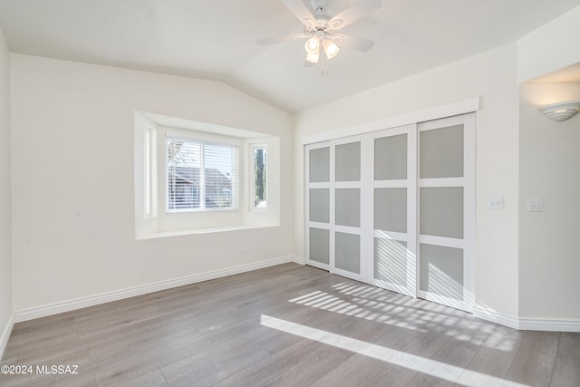 unfurnished room with ceiling fan, light wood-type flooring, and vaulted ceiling