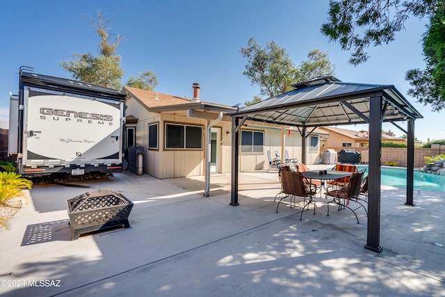 rear view of property featuring a fenced in pool, a gazebo, an outdoor fire pit, and a patio