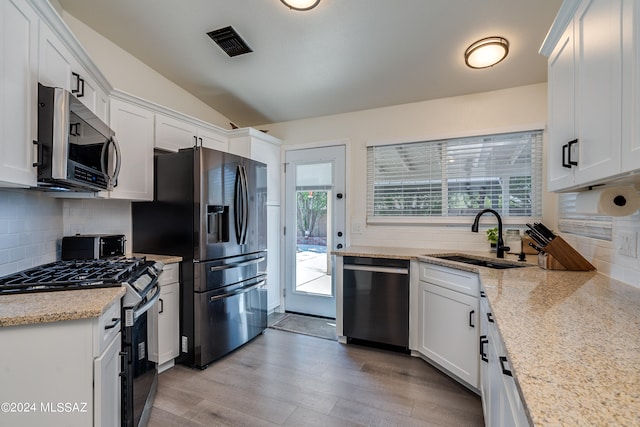 kitchen with lofted ceiling, a wealth of natural light, sink, white cabinetry, and stainless steel appliances