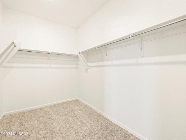 walk in closet with vaulted ceiling and carpet floors