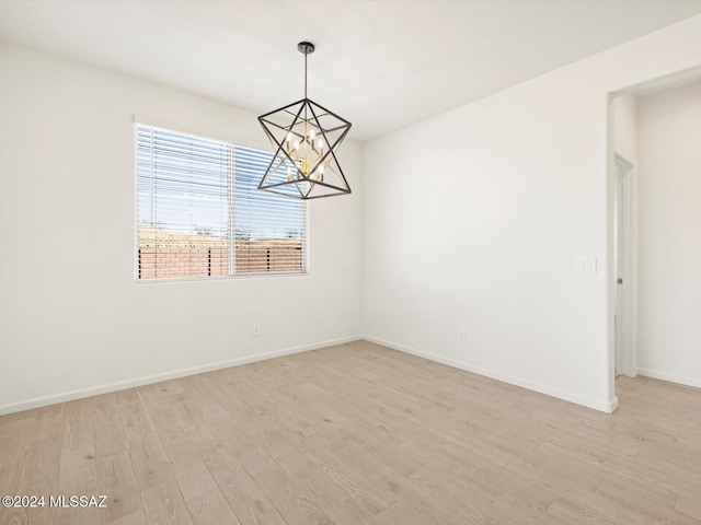 empty room featuring a chandelier and light wood-type flooring