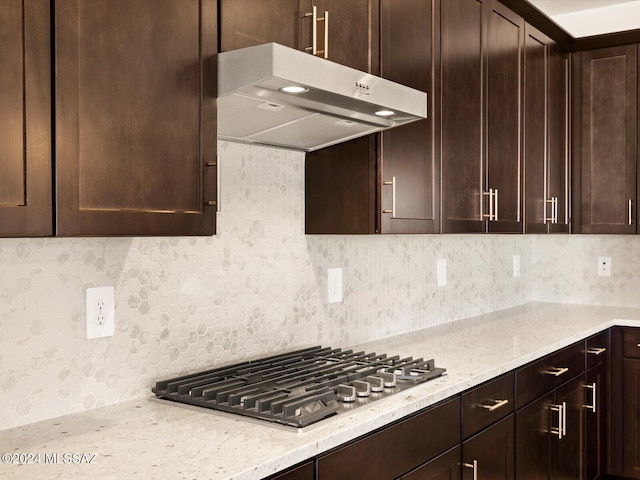 kitchen featuring dark brown cabinetry, decorative backsplash, light stone countertops, and stainless steel gas stovetop