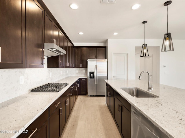 kitchen featuring sink, stainless steel appliances, light stone counters, dark brown cabinetry, and decorative backsplash