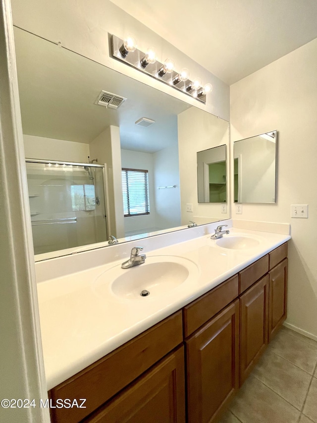 bathroom with an enclosed shower, vanity, and tile patterned flooring