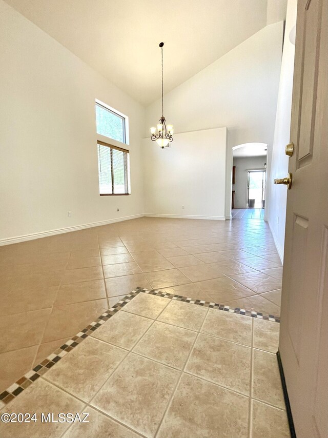 spare room with tile patterned floors, an inviting chandelier, and vaulted ceiling