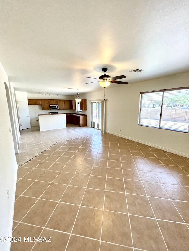 unfurnished living room with ceiling fan and light tile patterned flooring