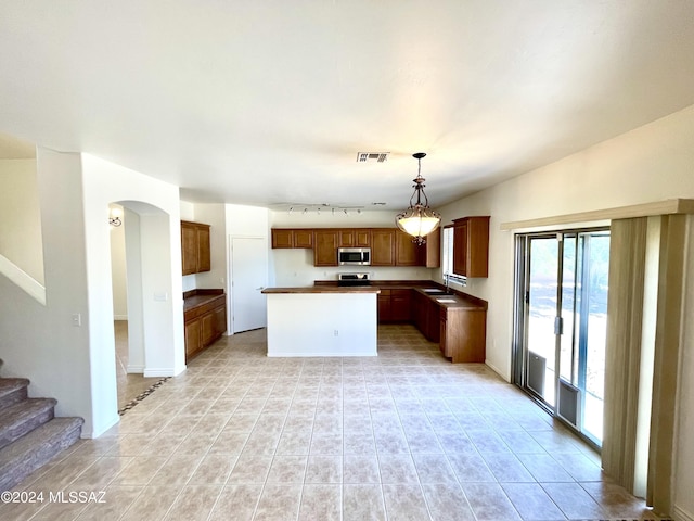 kitchen featuring hanging light fixtures, sink, light tile patterned flooring, and a center island