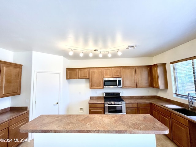 kitchen featuring light tile patterned flooring, sink, appliances with stainless steel finishes, and a kitchen island