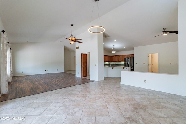 unfurnished living room featuring ceiling fan, light tile patterned flooring, lofted ceiling, and sink