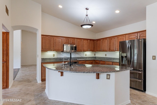 kitchen with decorative light fixtures, sink, an island with sink, stainless steel appliances, and high vaulted ceiling