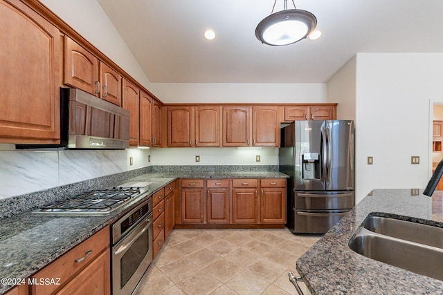 kitchen with appliances with stainless steel finishes, backsplash, dark stone counters, hanging light fixtures, and sink