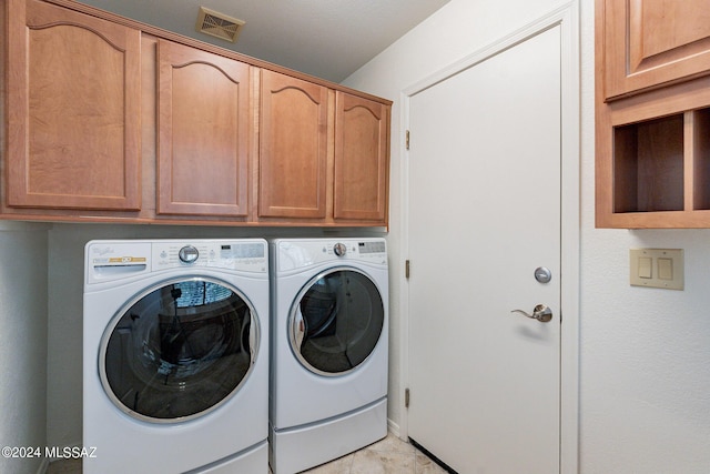 washroom featuring light tile patterned floors, separate washer and dryer, and cabinets